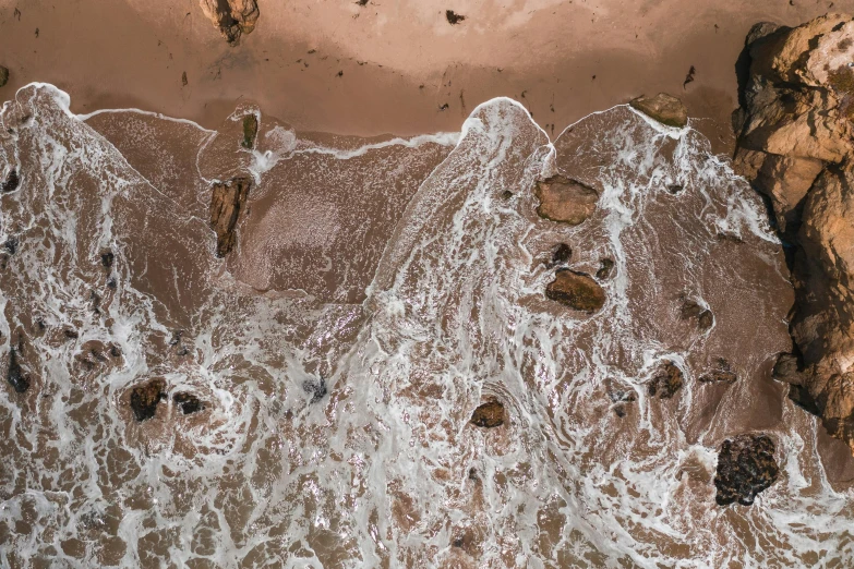 a person riding a surfboard on top of a sandy beach, by Lee Loughridge, unsplash contest winner, conceptual art, pink slime everywhere, looking down from above, rivulets, standing in a maelstrom