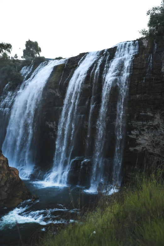 a man standing in front of a waterfall, hurufiyya, image from afar, australia, zoomed out view, riding