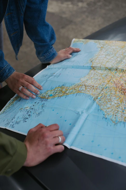 a couple of people that are looking at a map, hand on table, zoomed out to show entire image, us, operation