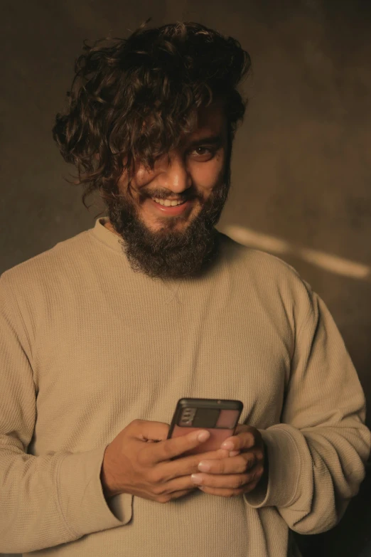 a man with a beard holding a cell phone, an album cover, inspired by Ismail Acar, trending on pexels, hurufiyya, brown messy hair, looking happy, smartphone photo, thicc
