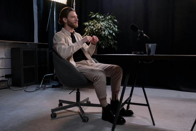 a man sitting in a chair in front of a microphone, a hologram, unsplash, hyperrealism, pewdiepie, office clothes, cinematic outfit photo