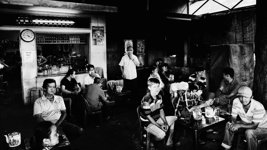 a group of people sitting around a table, a black and white photo, unsplash, south jakarta, local bar, medium format, trent parke