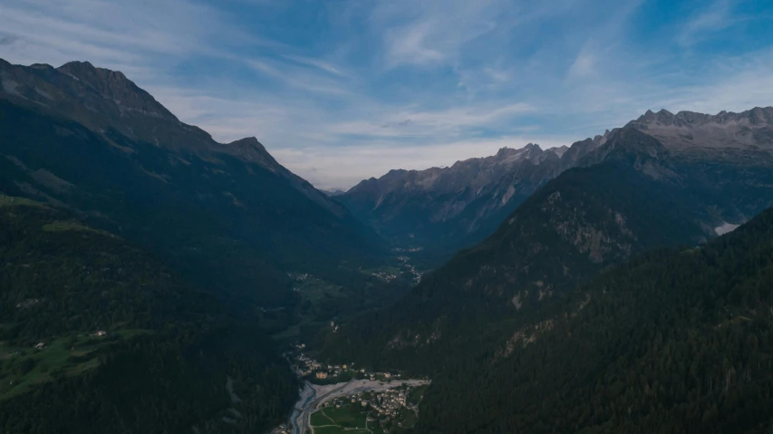 a view of a valley with mountains in the background, by Sebastian Spreng, pexels contest winner, aerial footage, chamonix, low light, low ultrawide shot