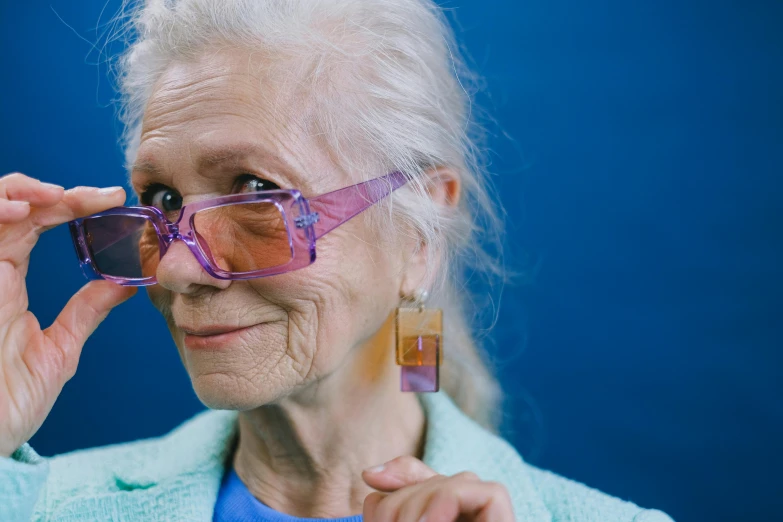 a close up of a person holding a pair of glasses, vivienne westwood, avatar image, an elderly, purple