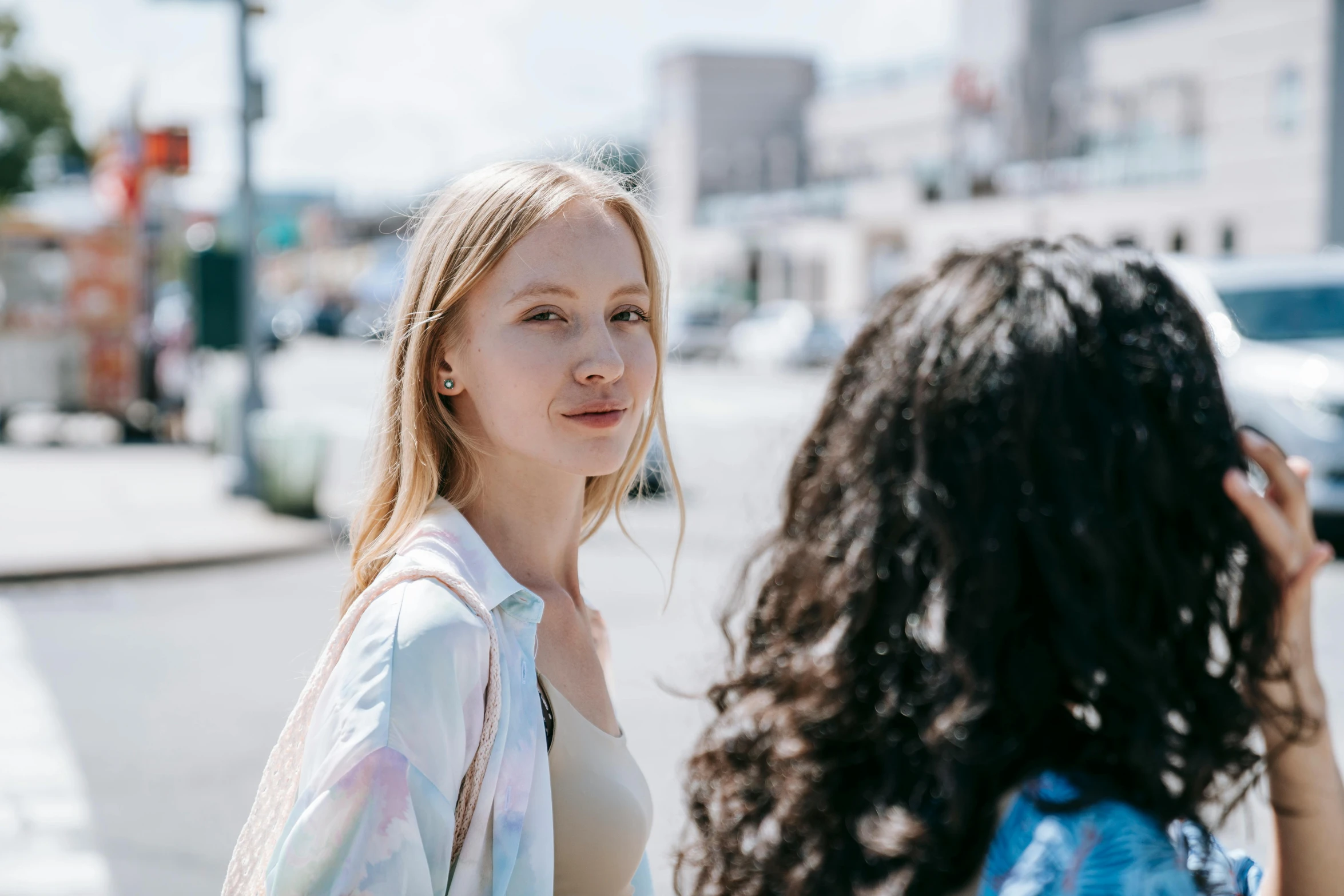 a woman taking a picture of another woman on the street, by Emma Andijewska, trending on pexels, realism, looking off to the side, diverse, sydney sweeney, side portrait of a girl