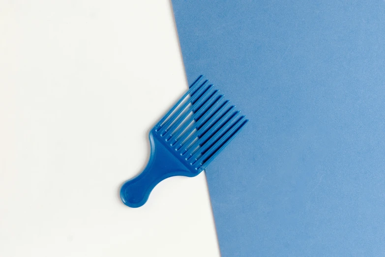 a blue comb on a blue and white background, inspired by Yves Klein, plasticien, afro comb, embossed paint, 35 mm product photo”, hair fluid