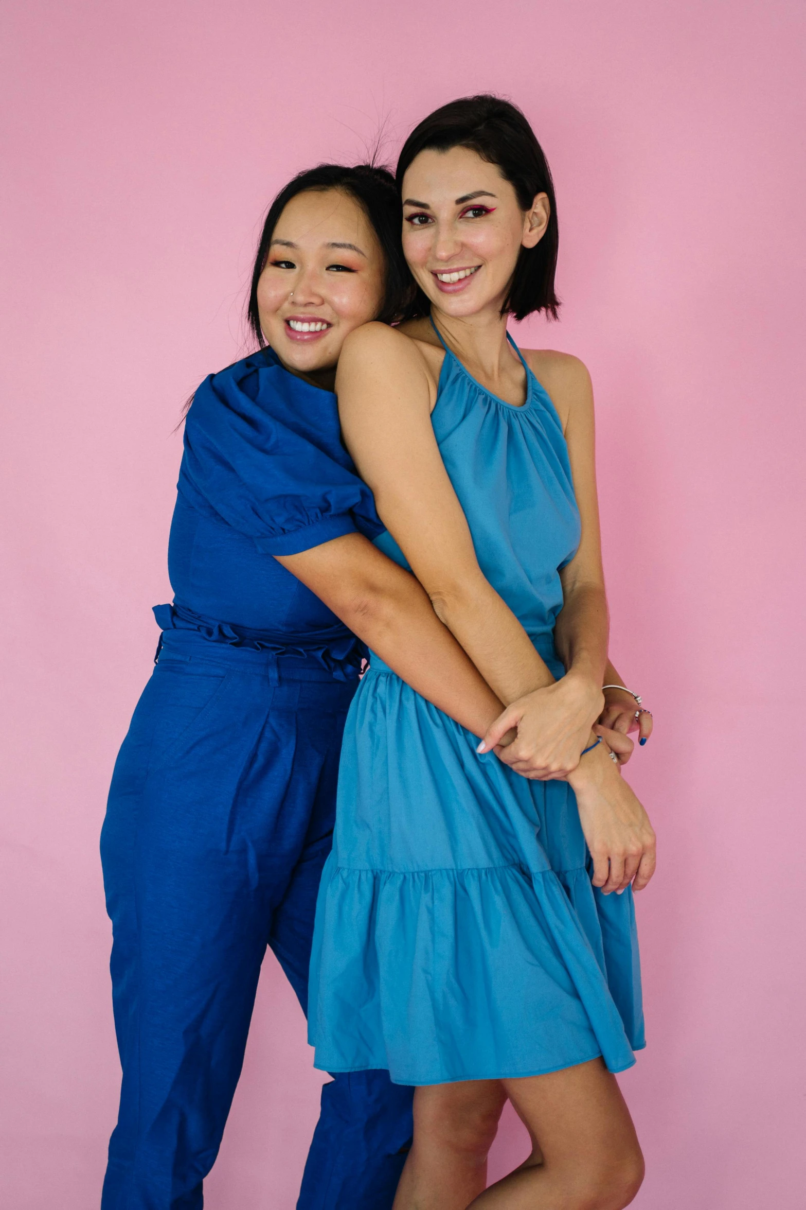 a couple of women standing next to each other, inspired by Wang Duo, pexels, dau-al-set, blue dress, half asian, modeling for dulce and gabanna, lgbtq