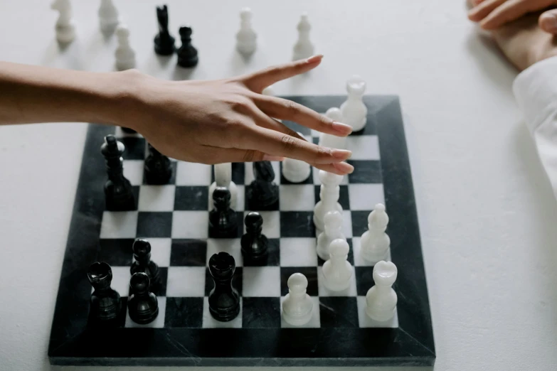 two people playing a game of chess on a table, a marble sculpture, trending on unsplash, hands reaching for her, white and black, closeup of hand, game resources