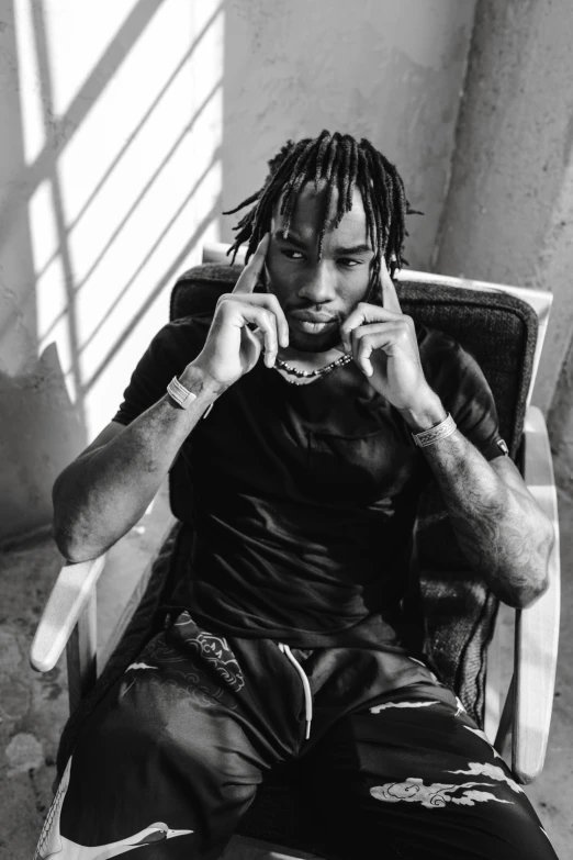 a man sitting in a chair talking on a cell phone, an album cover, trending on pexels, realism, playboi carti, cocky smirk, back and white, wearing chains