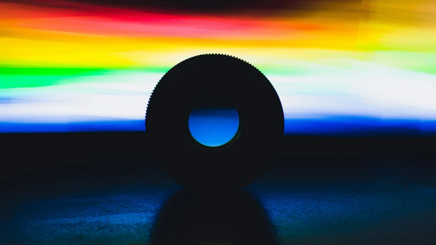 a close up of a tire with a colorful sky in the background, a microscopic photo, by Dan Luvisi, unsplash, → ⃣ spectrum darkness prime, blue and green light, volumetric lighting - n 9, a round minimalist behind