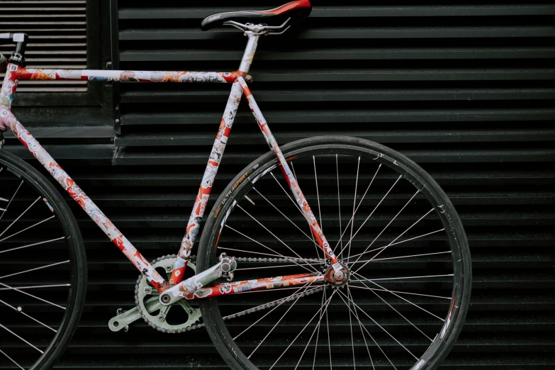 a close up of a bicycle parked in front of a building, inspired by Nagasawa Rosetsu, graffiti, on a gray background, paisley, it has a red and black paint, thumbnail