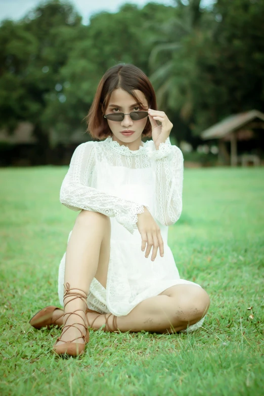 a woman sitting on top of a lush green field, inspired by Elsa Bleda, pexels contest winner, white soft leather model, with square glasses, asian, dress