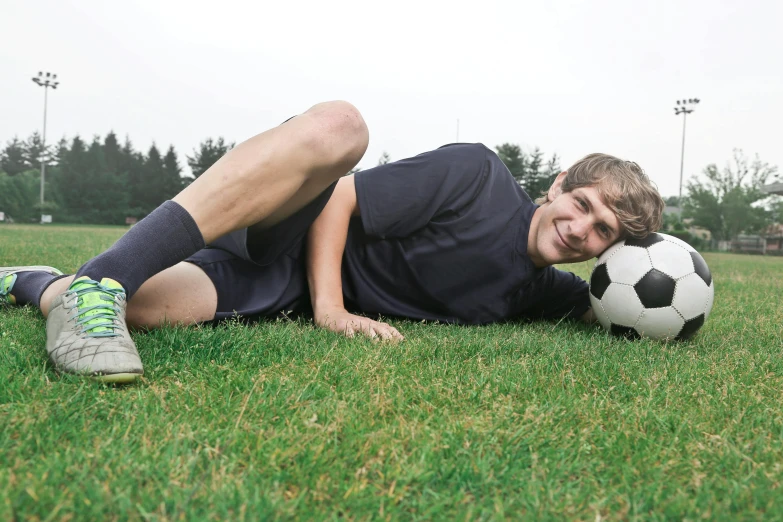 a young man laying on the ground with a soccer ball, lynn skordal, photo taken with provia, looking across the shoulder, hero pose
