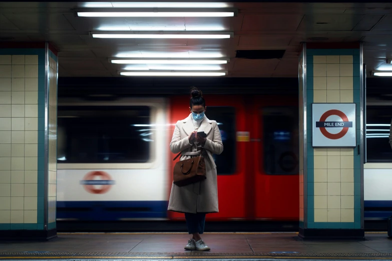 a woman standing in front of a subway train, unsplash, in london, pandemic, filmstill, reading