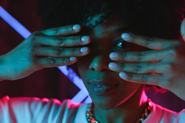 a woman covering her eyes with her hands, pexels contest winner, afrofuturism, subtle neon underlighting, looking at you, bisexual lighting, afro-psychedelia