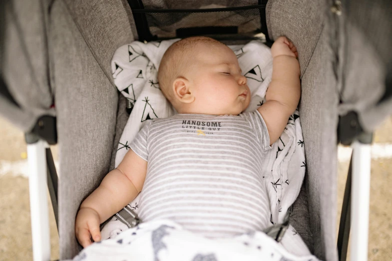 a baby is sleeping in a stroller, by Nina Hamnett, pexels contest winner, happening, grey, many stars, detail shot, handsome male