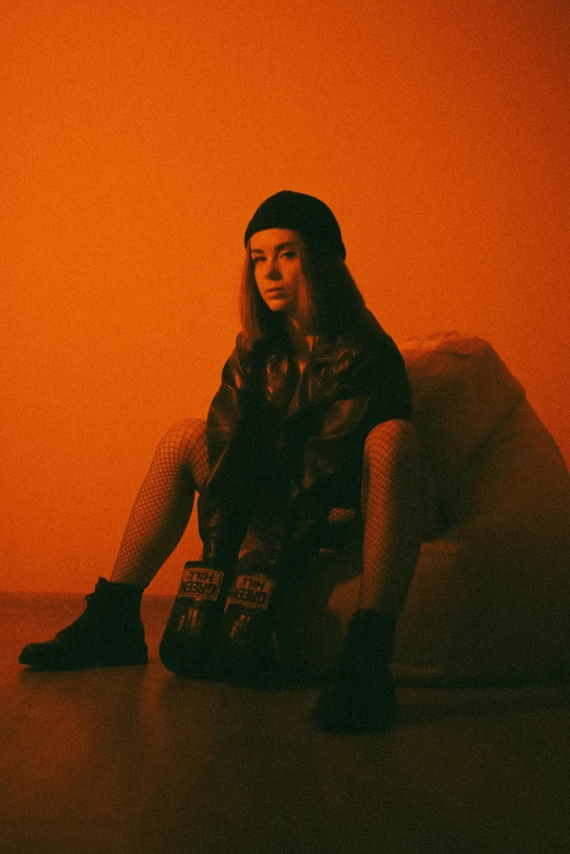 a woman sitting on top of a bean bag, an album cover, inspired by Elsa Bleda, trending on pexels, orange tint, portrait sophie mudd, wears a destroyed hat, in a pitch black room