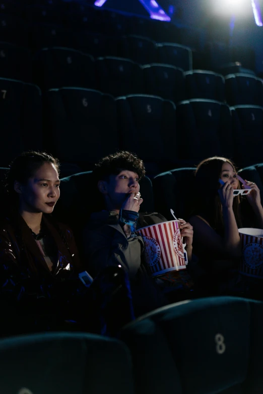 a group of people sitting in a theater watching a movie, pexels, hyperrealism, ross tran 8 k, eating, cinestill 800t 35mm eastmancolor, cinematic. by leng jun