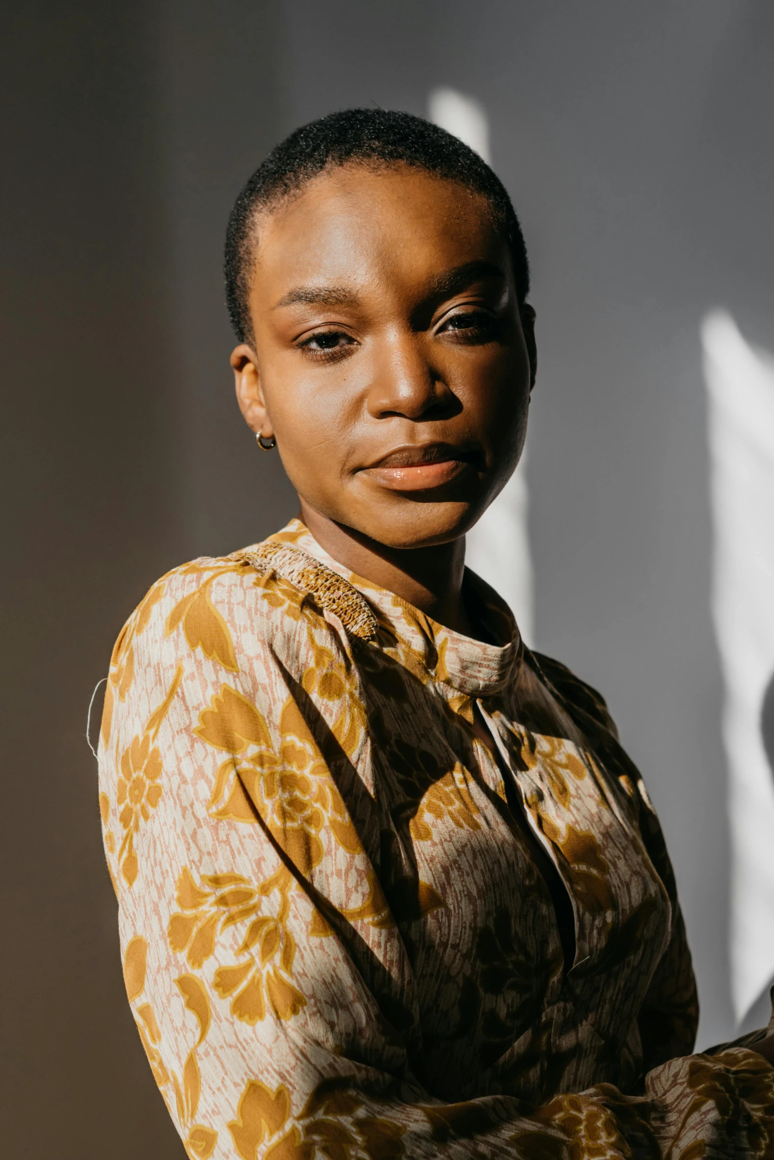 a woman standing in front of a window, by Winona Nelson, brown skin. light makeup, wearing yellow floral blouse, wide forehead, jovana rikalo