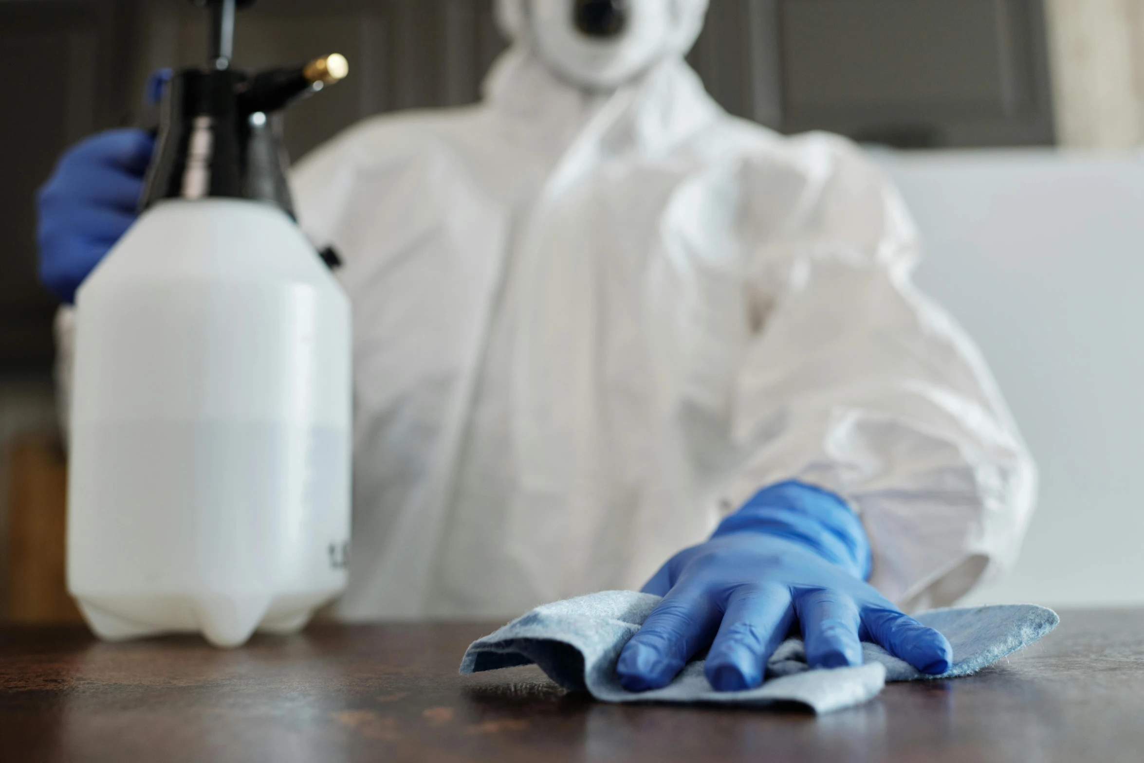 a man in a hazmat suit is cleaning a table, a portrait, by Daniel Lieske, shutterstock, fan favorite, spraying liquid, wearing lab coat and a blouse, at home