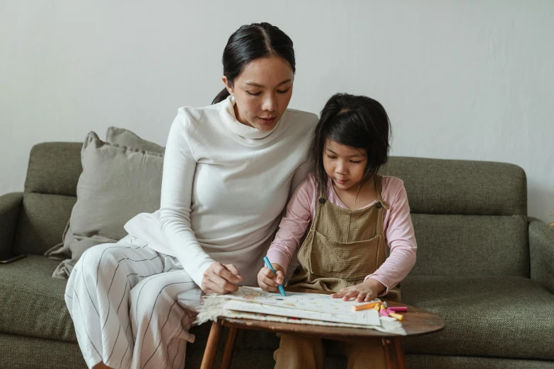 a woman and a little girl sitting on a couch, a child's drawing, pexels contest winner, sitting on a mocha-colored table, asian female, gif, maintenance photo