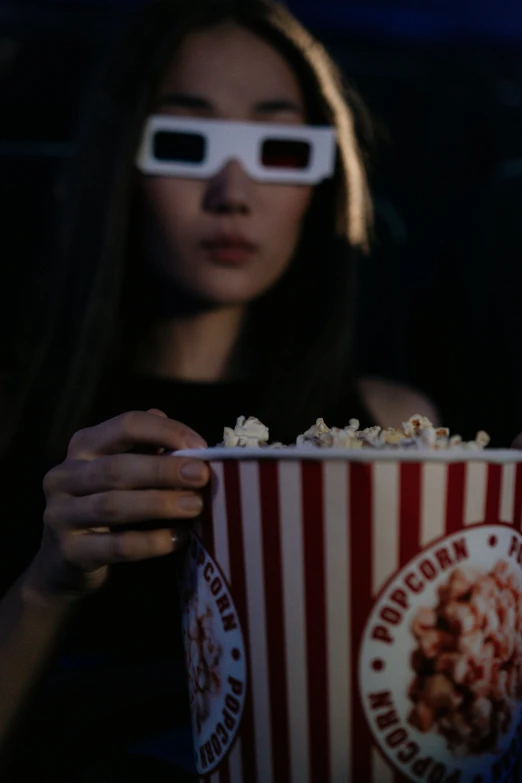 a woman in 3d glasses holding a box of popcorn, a hologram, inspired by Nan Goldin, trending on pexels, hyperrealism, night, hd movie photo, [ cinematic, superhero movie