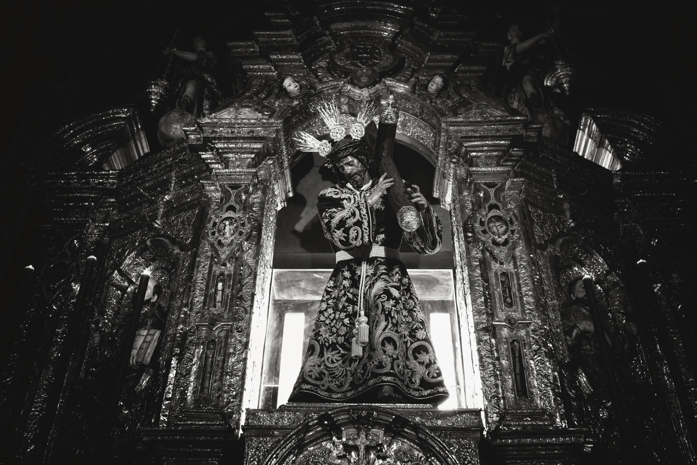 a black and white photo of the inside of a church, a statue, unsplash, baroque, mexican folklore, elaborate cult robes, album cover, made of intricate metal and wood