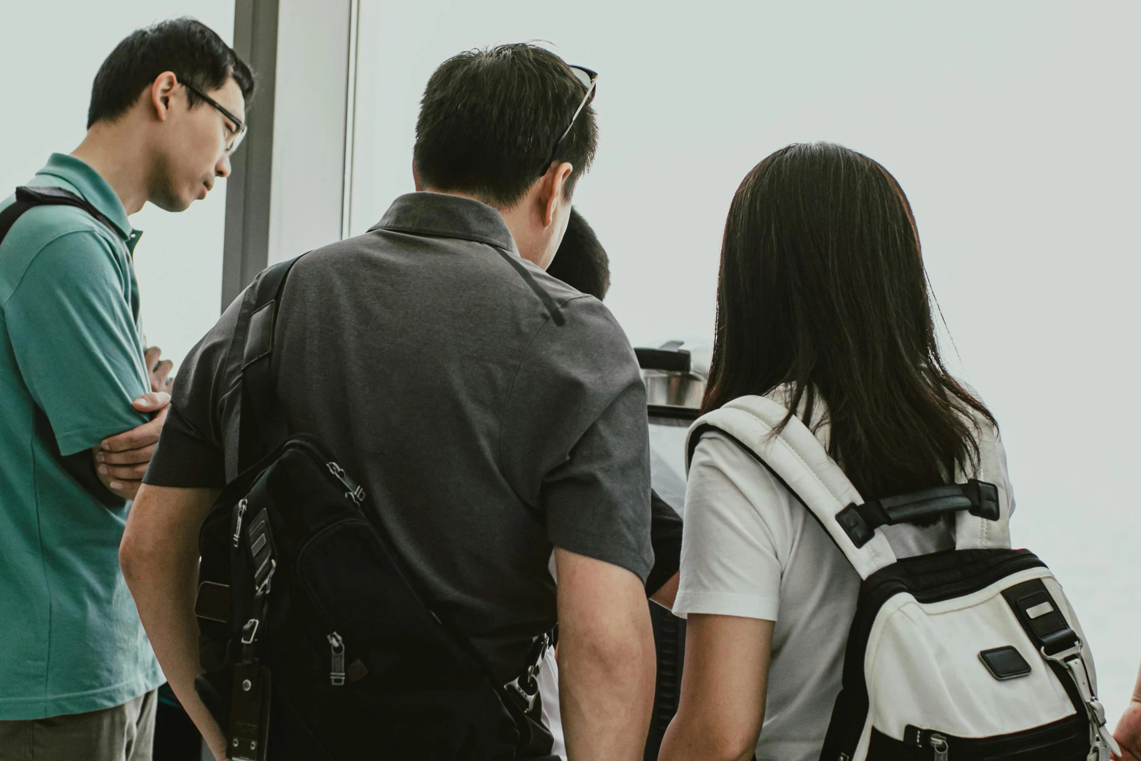 a group of people standing next to each other, by Reuben Tam, pexels contest winner, happening, a backpack, server in the middle, taken from a plane, looking partly to the left