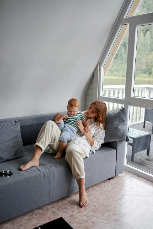 a woman and a child are sitting on a couch, filled with natural light, comfy chairs, grey, toddler