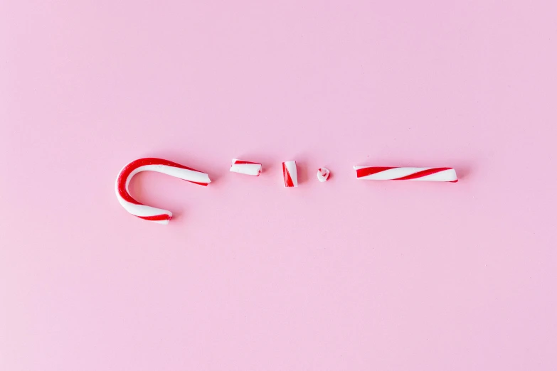 two candy canes on a pink background, inspired by Cerith Wyn Evans, trending on pexels, minimalism, ffffound, the grinch, knolling, letter s