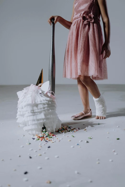 a little girl in a pink dress standing next to a cake, an album cover, inspired by Frieke Janssens, pexels contest winner, magic realism, scattered rubbish, unicorn from the tusk movie, shows a leg, detail shot