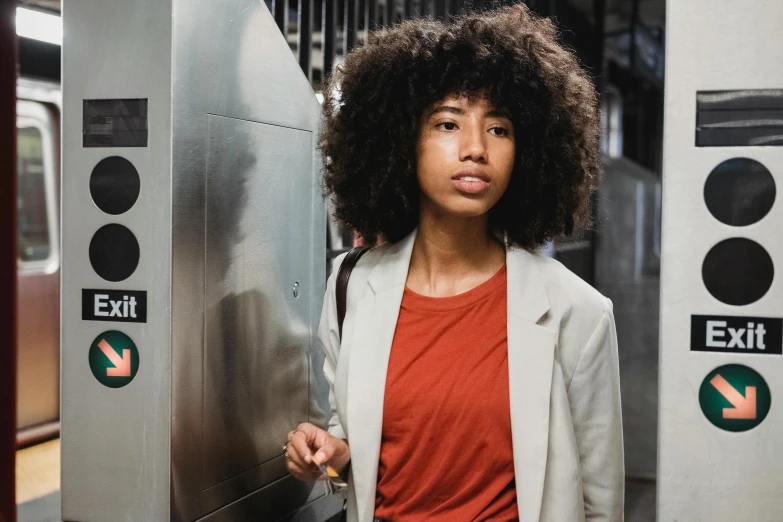 a woman standing in front of an exit sign, pexels contest winner, mta subway entrance, afro hair, elevator, handsome girl