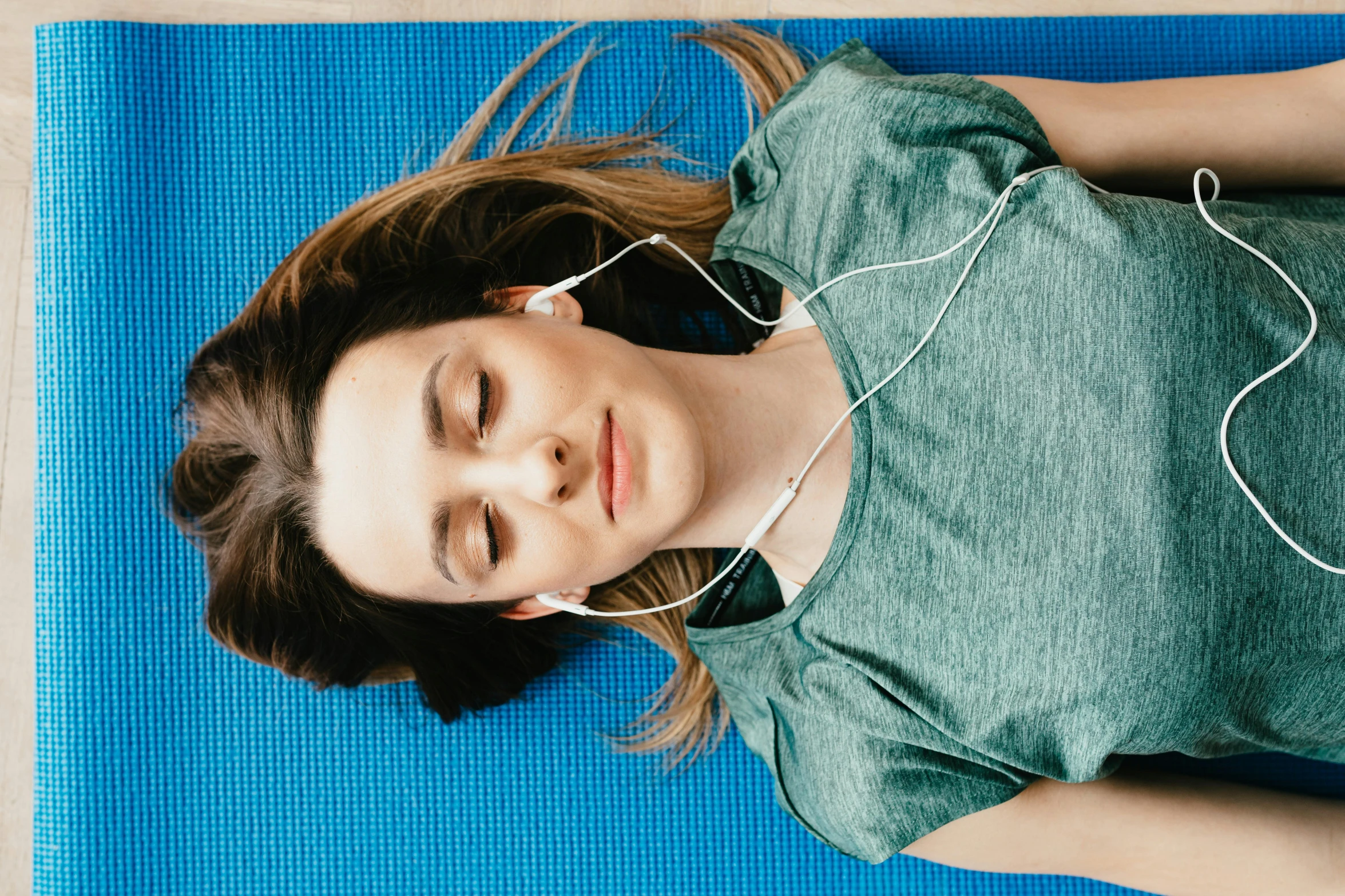 a woman laying on a yoga mat with headphones on, trending on pexels, hurufiyya, acupuncture treatment, avatar image, blue, instagram picture