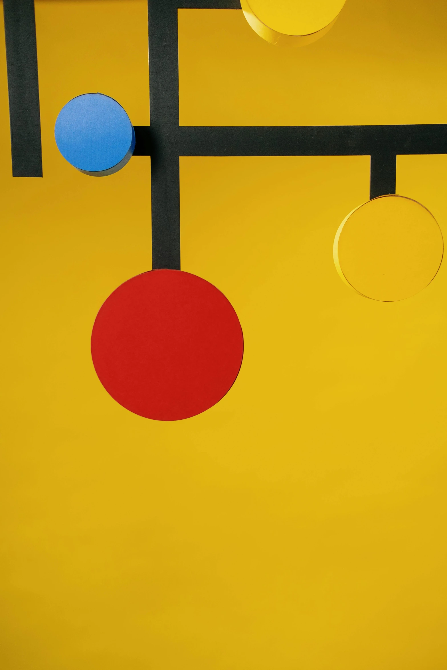 a yellow wall with red, blue, and yellow circles hanging from it, an abstract sculpture, inspired by Bauhaus, de stijl, photography ultrafine detail, 1 9 6 6, studio backdrop, colors: yellow