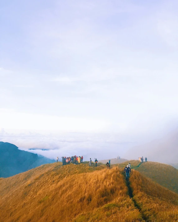 a group of people standing on top of a mountain, by Jessie Algie, pexels contest winner, sumatraism, instagram story, rolling hills, zoomed out, ligjt trail