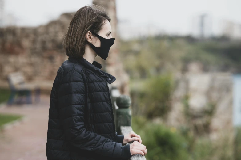 a woman in a black jacket and a black face mask, pexels contest winner, renaissance, city ruins in the background, avatar image, side view profile, air pollution