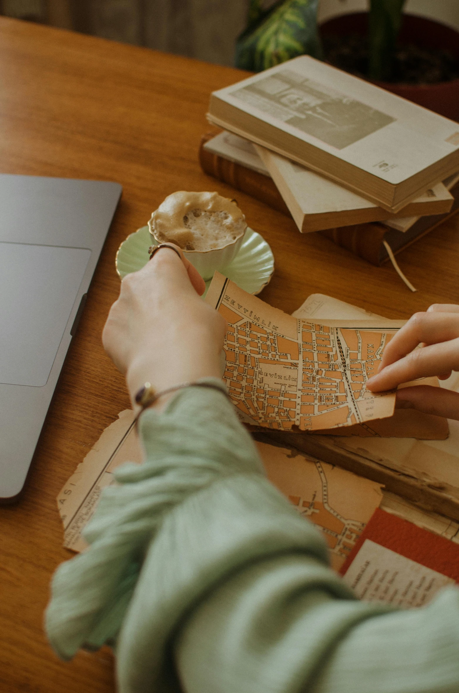 a person sitting at a table with a laptop, a colorized photo, by Jessie Algie, trending on pexels, marauders map, holding a wood piece, urban planning, cake in hand