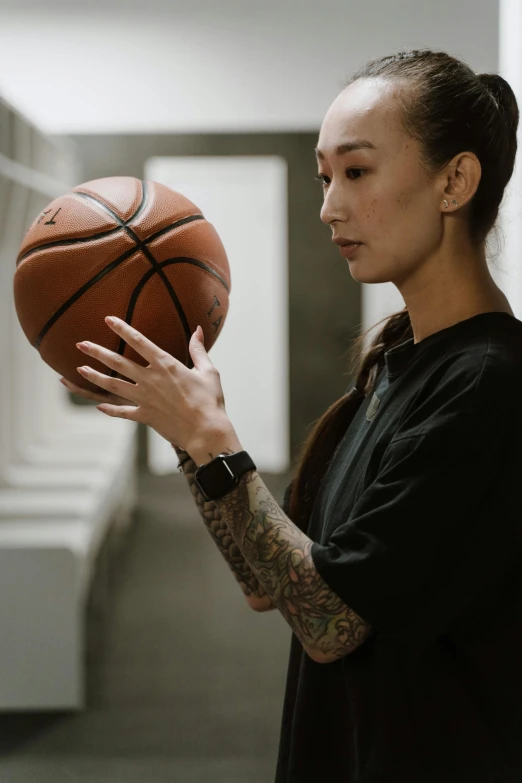 a woman holding a basketball up to her face, a tattoo, trending on dribble, wears a watch, mei-ling zhou, profile image, low ultrawide shot