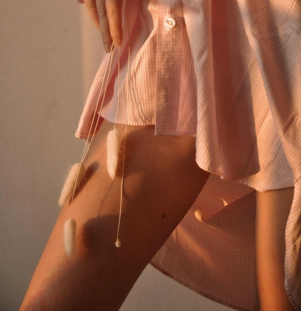 a close up of a person wearing a pink shirt, inspired by Elsa Bleda, trending on pexels, short skirt, strings of pearls, pale light, bunny leg