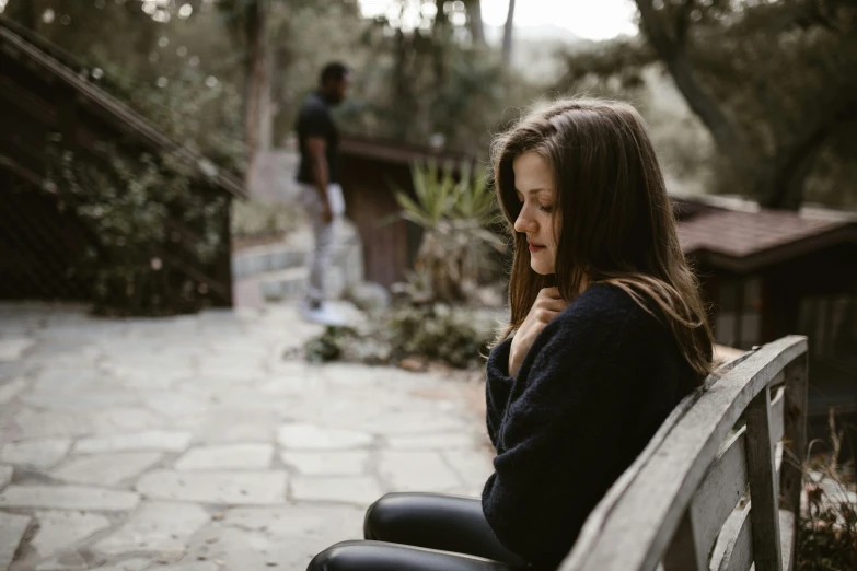 a woman sitting on top of a wooden bench, trending on pexels, realism, a very sad man, person in foreground, girl with brown hair, sitting in the garden