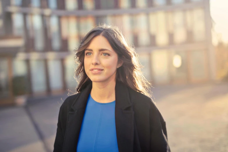 a woman in a blue shirt and black jacket, inspired by Anita Malfatti, pexels contest winner, alison brie, architect, morning golden hour, aluminium