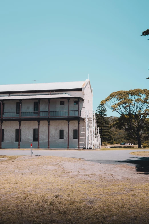 a large building sitting in the middle of a field, a colorized photo, inspired by Sydney Prior Hall, unsplash, coastline, barracks, war theatre, photo taken on fujifilm superia