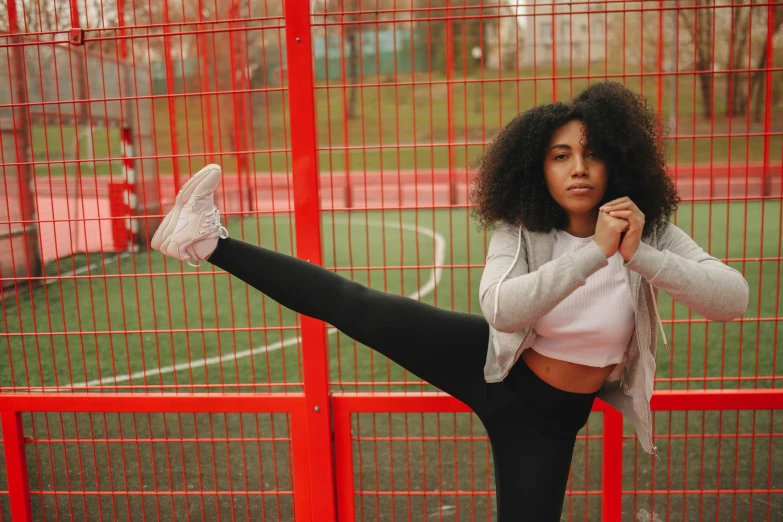 a beautiful young woman standing on top of a soccer field, pexels contest winner, arabesque, pretty samurai with afro, black leggins, standing astride a gate, karate pose