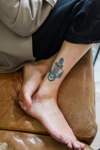 a person sitting on a couch with a tattoo on their foot, a tattoo, trending on pexels, deep sea themed, square, maritime, pastel'