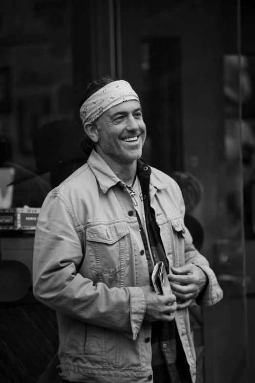 a black and white photo of a man wearing a bandana, by Tom Bonson, smiling coyly, street life, robert downey jr, greig fraser