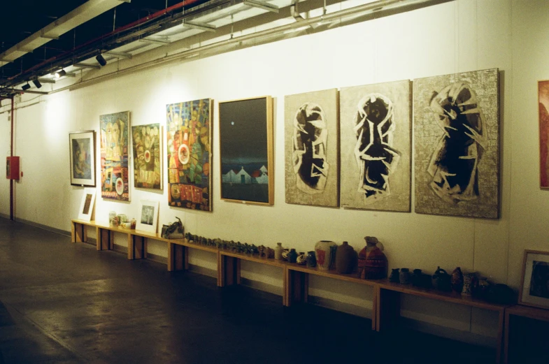 a number of paintings on a wall in a room, bengal school of art, 2000s photo, night time, ceramics, harlem