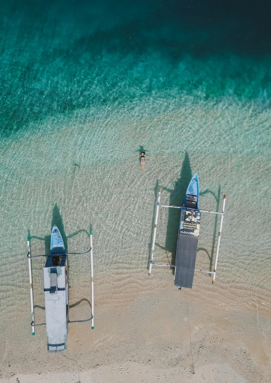 a couple of boats sitting on top of a sandy beach, birdseye view, crystal clear blue water, bali, slide show