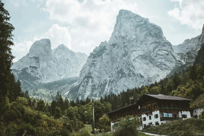 a house sitting on top of a lush green hillside, by Sebastian Spreng, pexels contest winner, icy mountains in the background, vintage vibe, seen from below, ready to eat