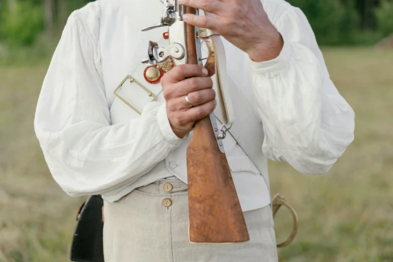 a man standing in a field holding a rifle, unsplash, renaissance, white waistcoat, holding a bell, close-up photo, historical event