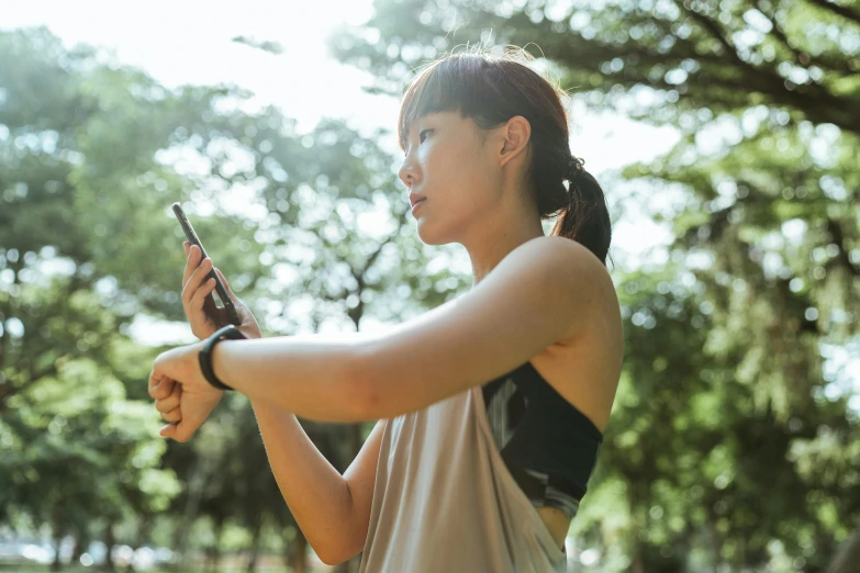 a woman holding a cell phone in a park, trending on pexels, workout, of taiwanese girl with tattoos, avatar image, square